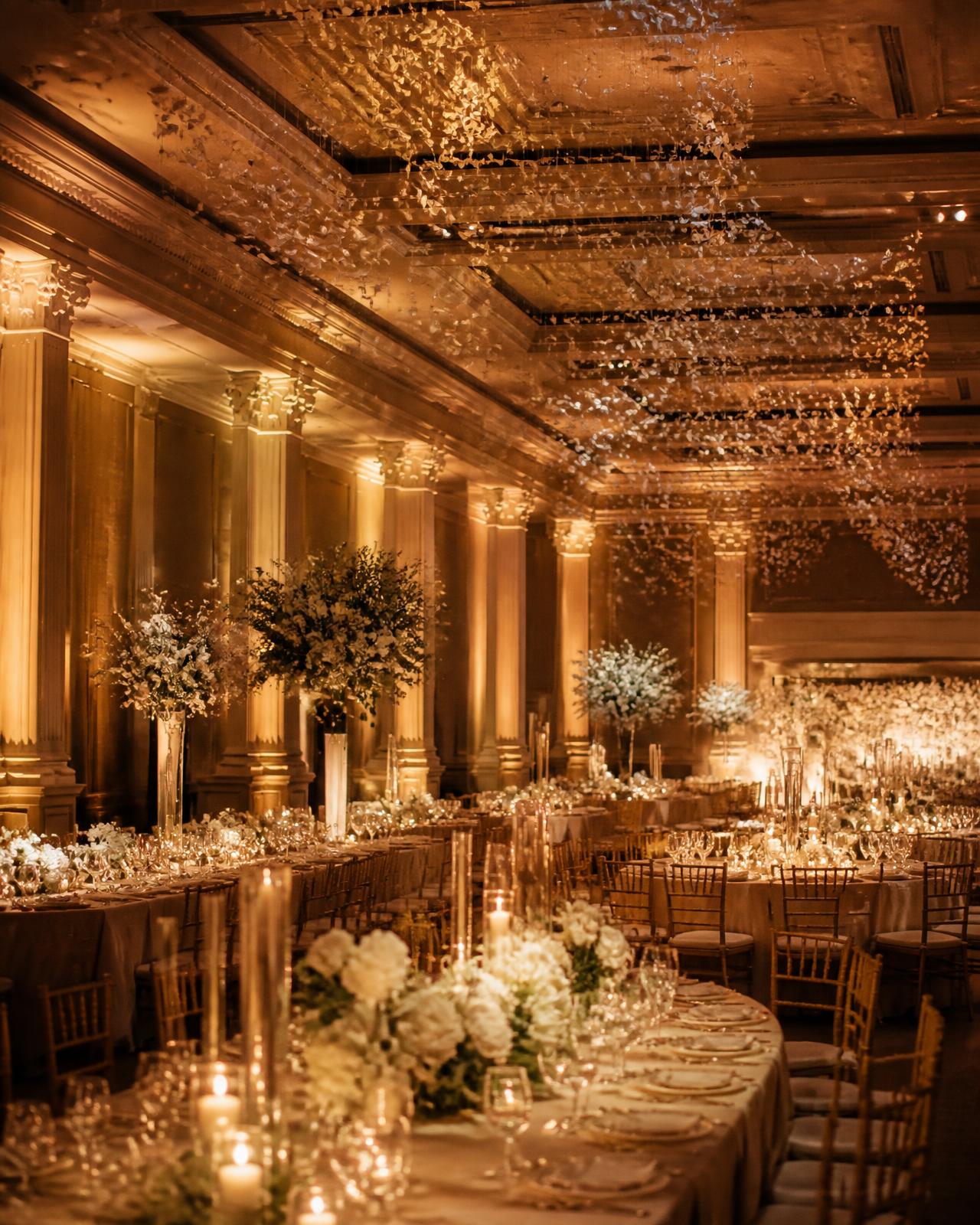 An elegant event venue transformed by warm architectural uplighting and suspended light installations